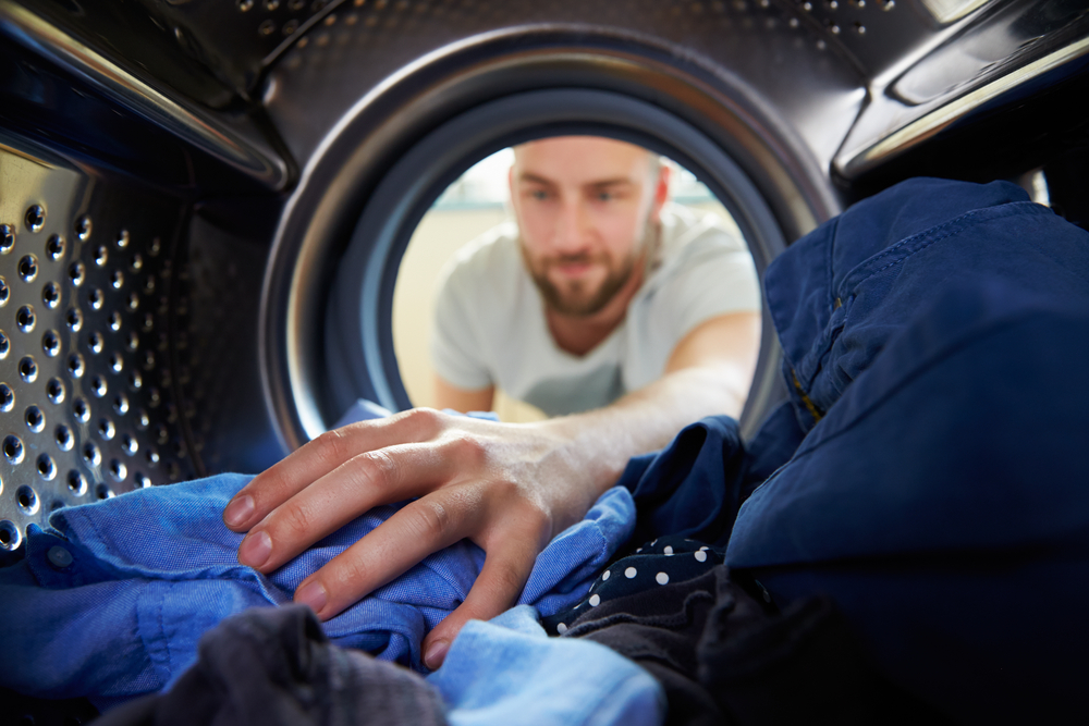 Man,Doing,Laundry,Reaching,Inside,Washing,Machine