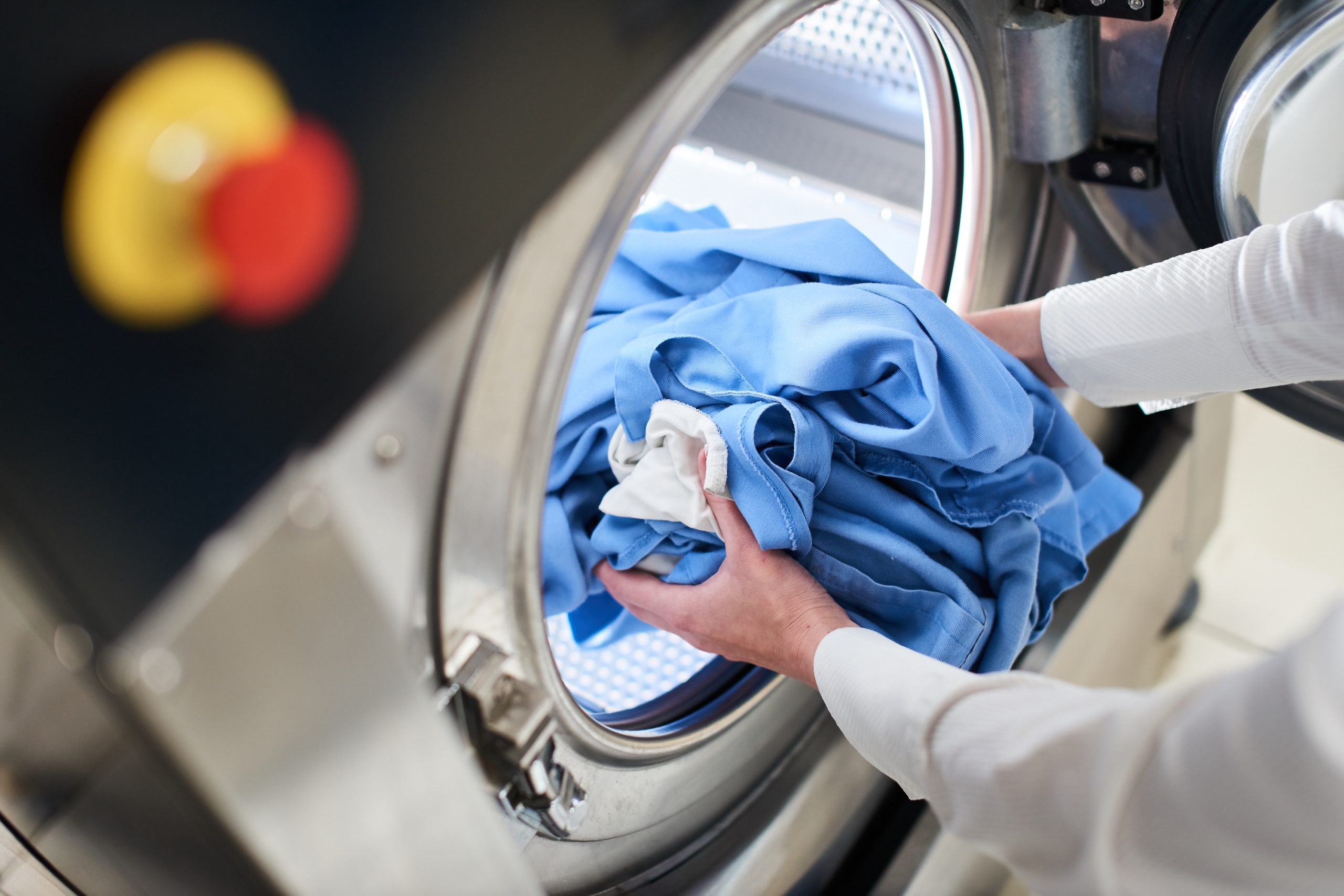 person placing clothes in washing machine